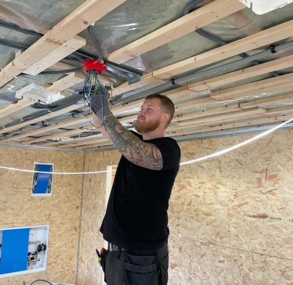 Elektriker Skåne utför elinstallation i nybyggt hus med synliga kablar.